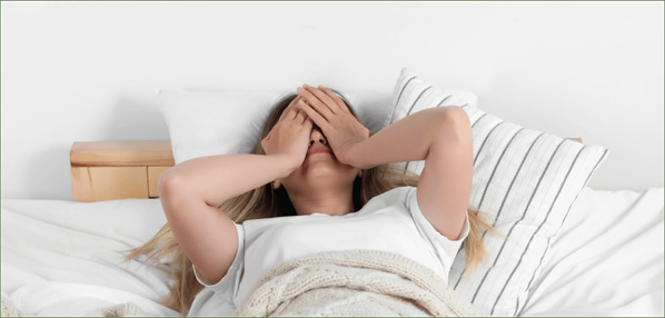 KI generiert: Eine Frau liegt im Bett und hält sich die Hände vors Gesicht.