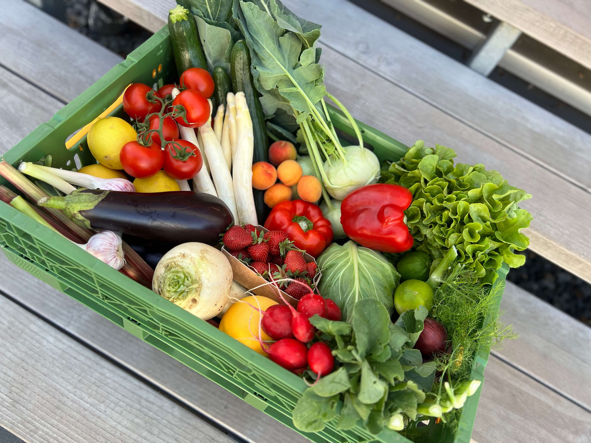 KI generiert: Ein grüner Korb mit frischem Obst und Gemüse auf Holzboden.