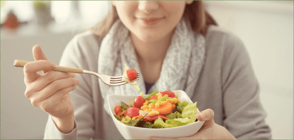KI generiert: Eine Frau isst einen frischen Salat mit Tomaten und Karotten.
