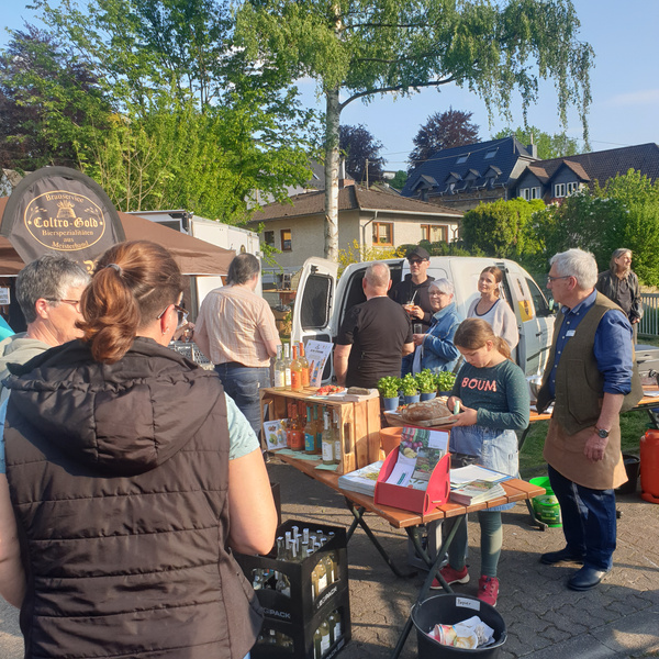 KI generiert: Menschen auf einem Markt mit Ständen, Getränken und Pflanzen. Text: "Boulevard Coltro-Gold Bierprobiationen."