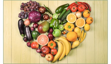 KI generiert: Obst und Gemüse in Herzform auf einem Holzhintergrund.