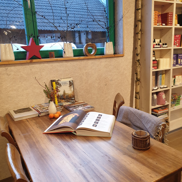 KI generiert: Ein gemütlicher Tisch mit Büchern und Deko neben einem Regal voller Produkte.