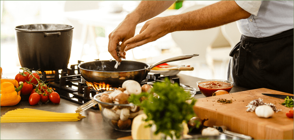 KI generiert: Ein Koch bereitet in einer Küche mit frischen Zutaten eine Mahlzeit zu. Es gibt keinen Text im Bild.