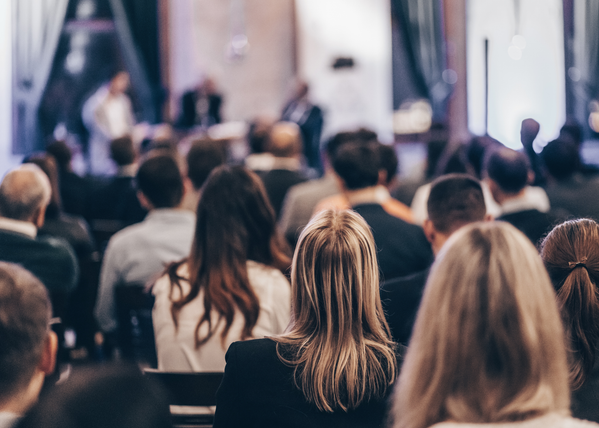 KI generiert: Menschen in einem Konferenzraum, alle sitzen und hören anscheinend einer Diskussion zu.