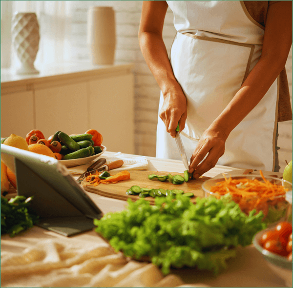 KI generiert: Person schneidet Gemüse in einer Küche, mit einem Tablet daneben.