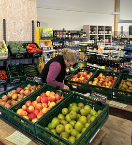 Kundin beim Einkaufen im Hofladen mit frischem Obst und Gemüse