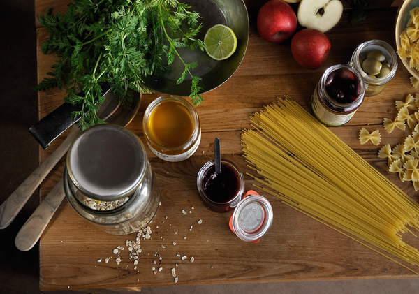 KI generiert: Eine Küchentisch-Szene mit Pasta, frischen Lebensmitteln, Gläsern und Gewürzen.