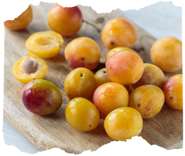 KI generiert: Gelbe Mirabellen auf einem Holzbrett, teils halbiert und mit sichtbaren Kernen.